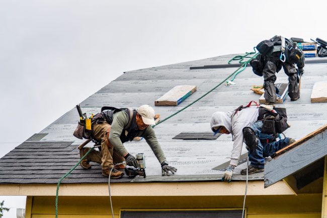 Everett WA. USA - 03-23-2021: Crew Installing New Shingles on Roof on a Rainy Day